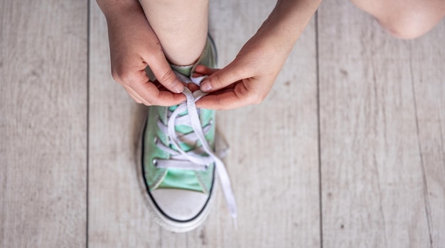 Bezpłatne zdjęcie dziecko z powodzeniem wiąże buty z bliska na stopach