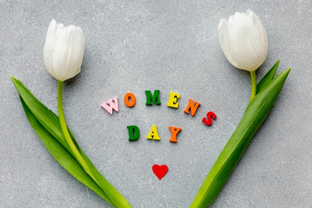 Bezpłatne zdjęcie dzień kobiet napis na cemencie z białymi tulipanami
