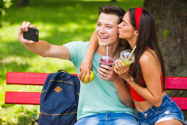 Dziewczyna całuje jej chłopak bierze selfie w parku