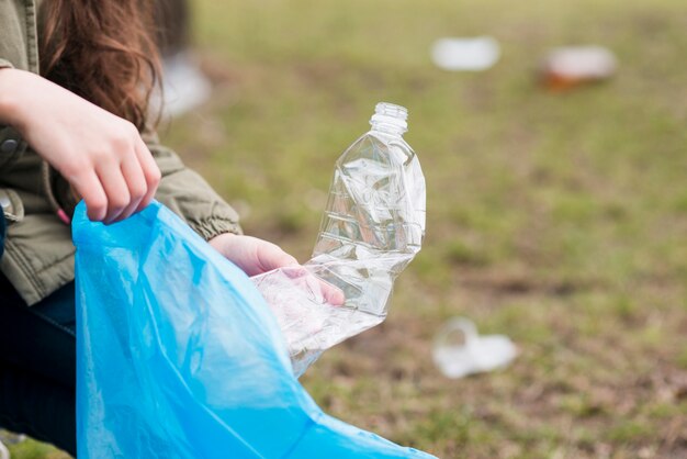 Dziewczyna czyści plastikową butelkę od ziemi