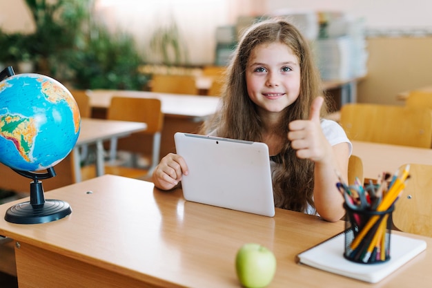 Bezpłatne zdjęcie dziewczyna gestykuluje kciuk z tabletem