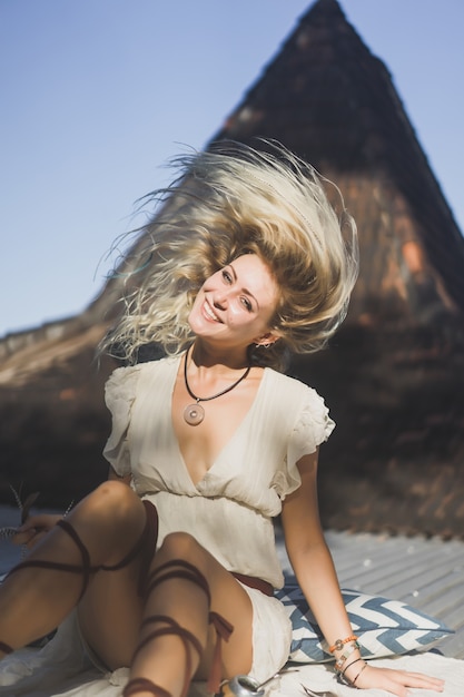 dziewczyna hipis z długimi blond włosami w sukience na dachu.