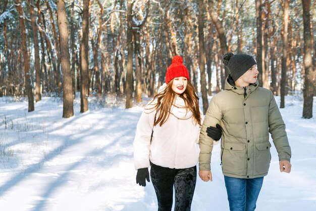 Dziewczyna i facet spacerują w parku zimowym. młoda para w śnieżnym lesie.