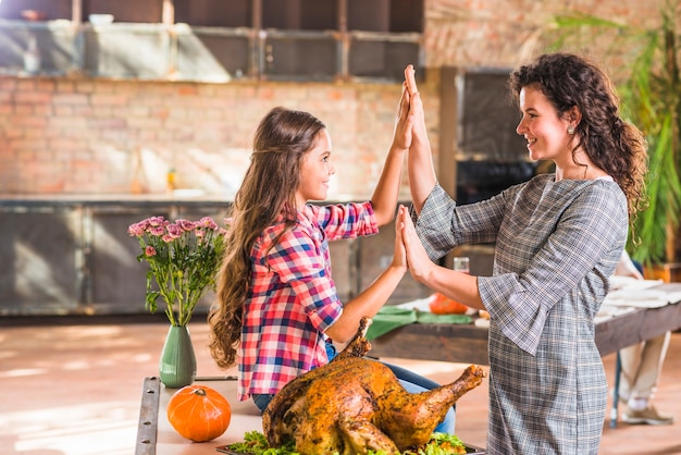 Bezpłatne zdjęcie dziewczyna i kobieta trzymając się za ręce w pobliżu pieczonego kurczaka