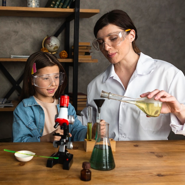 Bezpłatne zdjęcie dziewczyna i nauczycielka robi eksperymenty naukowe