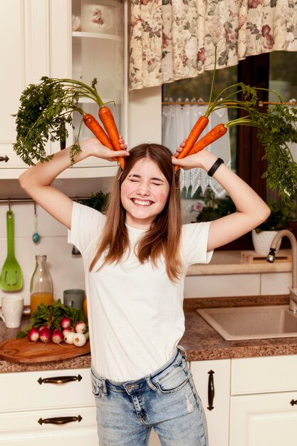 Dziewczyna ma zabawę z marchewkami w kuchni