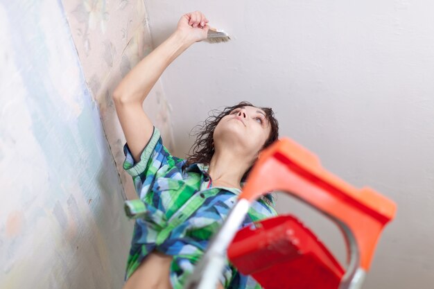 Dziewczyna maluje sufit w domu
