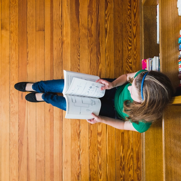 Bezpłatne zdjęcie dziewczyna na podłogowej czytelniczej książce z mapami