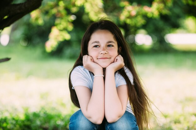 Dziewczyna oparty na ręce uśmiecha się w parku