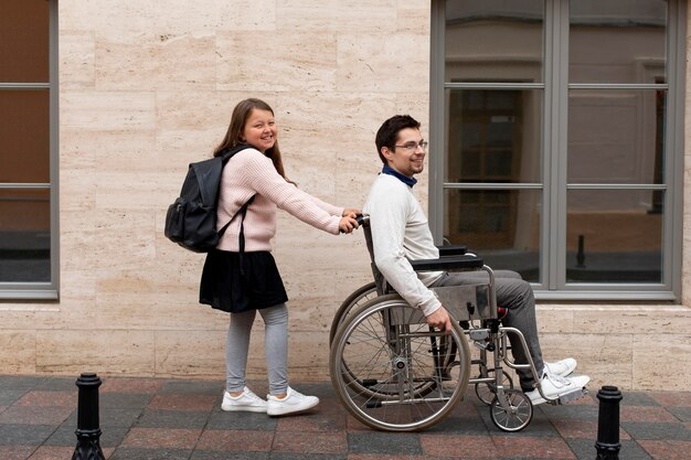 Dziewczyna pomaga niepełnosprawnemu mężczyźnie podróżującemu po mieście