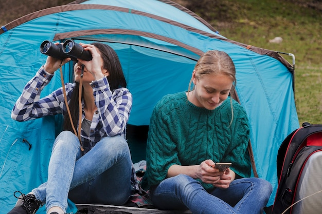 Dziewczyna przy użyciu jej lornetki obok swojego przyjaciela z jej telefonu komórkowego