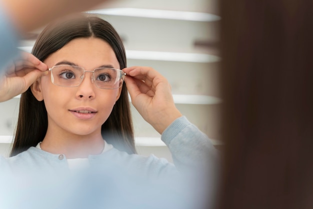 Bezpłatne zdjęcie dziewczyna przymierza okulary w sklepie okularów