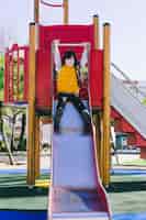 Bezpłatne zdjęcie dziewczyna siedzi na slajdzie plac zabaw dla dzieci