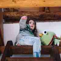 Bezpłatne zdjęcie dziewczyna siedzi na szczycie klatki schodowej z miękkiej zabawki