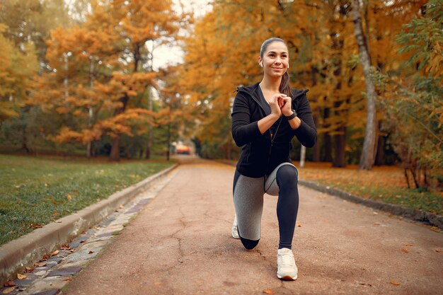 Dziewczyna sportowa w czarnym top szkolenia w parku jesienią