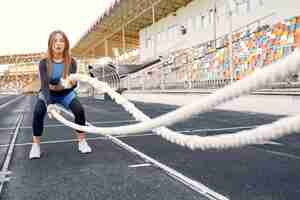 Bezpłatne zdjęcie dziewczyna sportowa w niebieskim mundurze szkolenia na stadionie z liny