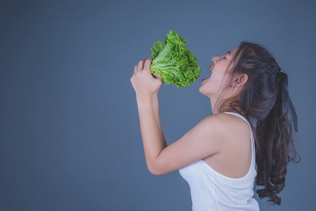 Dziewczyna trzyma warzywa na szarym tle.