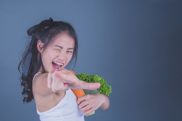 Dziewczyna trzyma warzywa na szarym tle.