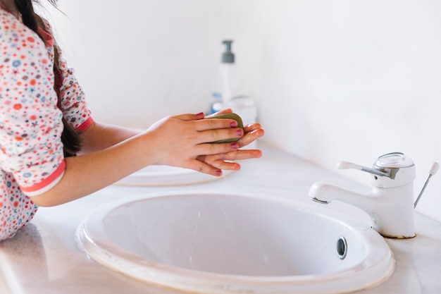 Dziewczyna używa mydło na jej rękach w łazience