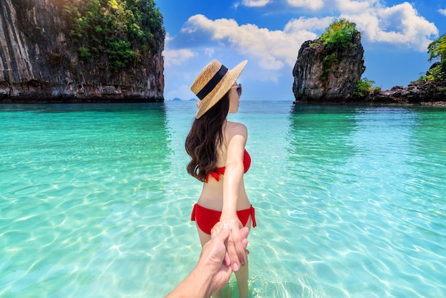 Dziewczyna w bikini trzymająca mężczyznę za rękę i prowadząca go na wyspę koh hong w Krabi, Tajlandia