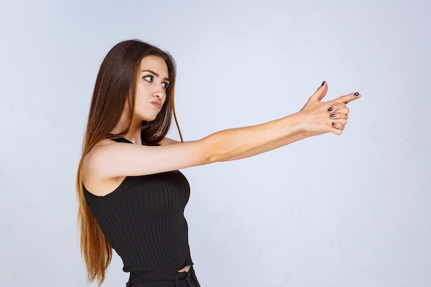 Bezpłatne zdjęcie dziewczyna w czarnej koszuli dokonywanie ręka pistolet znak.