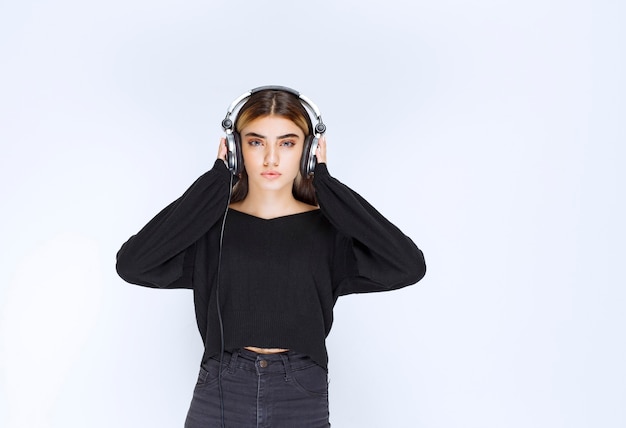 Dziewczyna w czarnej koszuli na sobie słuchawki i słuchanie muzyki. zdjęcie wysokiej jakości