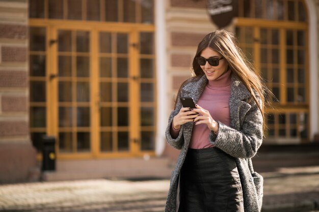 Dziewczyna w płaszczu z telefonu stojącego na ulicy