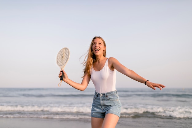 Dziewczyna w podkoszulek i spodenki grać w tenisa na brzegu morza