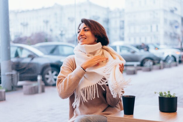 Dziewczyna w przytulnej kawiarni ogrzewa się filiżanką gorącej kawy