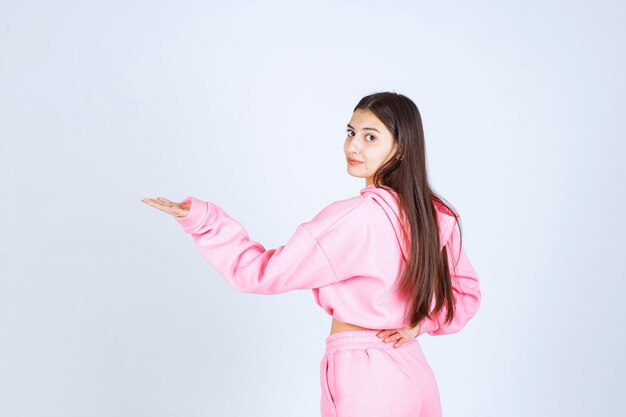 Dziewczyna w różowej piżamie wskazując na coś po lewej stronie