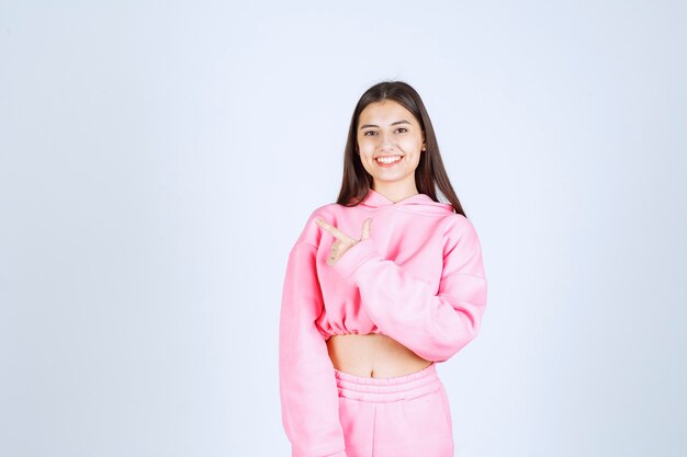 Dziewczyna w różowej piżamie wskazując na coś po lewej stronie