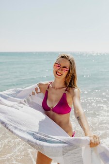 Dziewczyna w różowym bikini z ręcznikiem na plaży