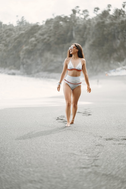 Dziewczyna w stylowym stroju kąpielowym ma odpoczynek na plaży