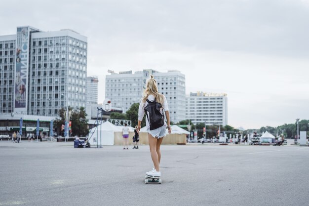 dziewczyna z długimi włosami łyżwy na deskorolce. ulica, aktywny sport