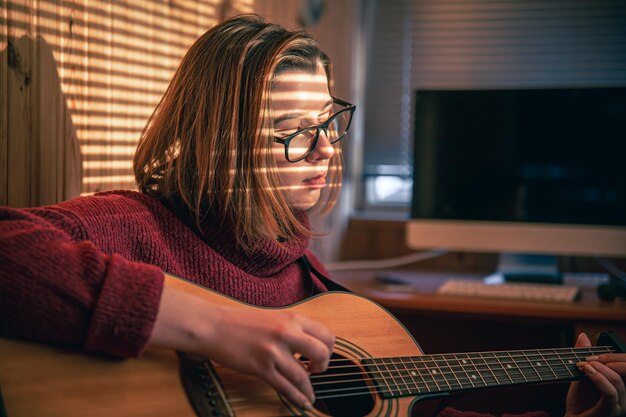 Dziewczyna z gitarą w słońcu przez żaluzje