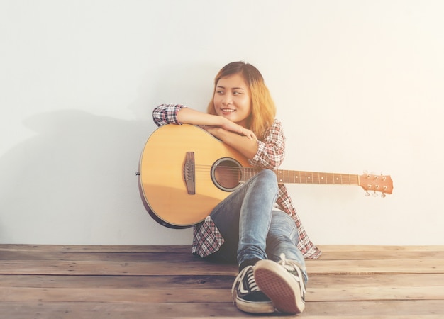 Dziewczyna z guitarr siedzi na podłodze