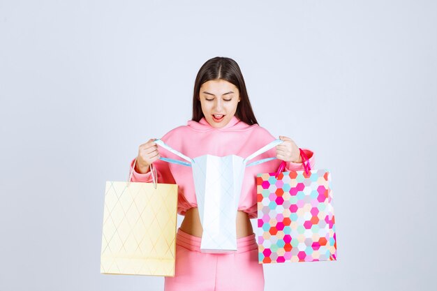 Dziewczyna z kolorowymi torbami na zakupy, otwierając je i sprawdzając.