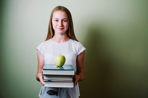 Bezpłatne zdjęcie dziewczyna z książek i jabłko