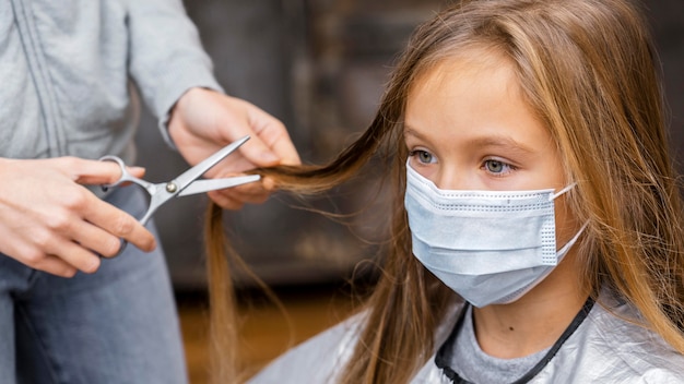 Dziewczyna z maską medyczną u fryzjera