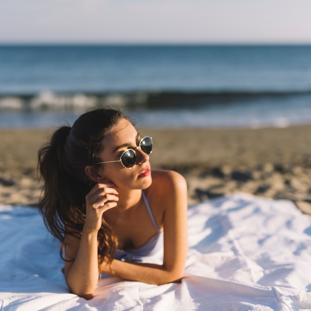 Dziewczyna z okulary słoneczne leżącego na plaży