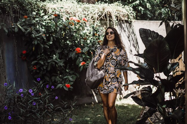 dziewczyna z plecakiem, w okularach przeciwsłonecznych, w tropikalnym ogrodzie