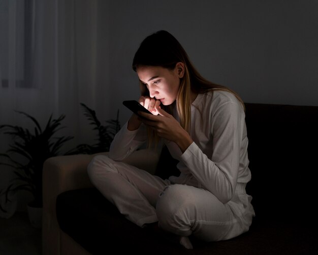 Dziewczyna z telefonem komórkowym w nocy w łóżku