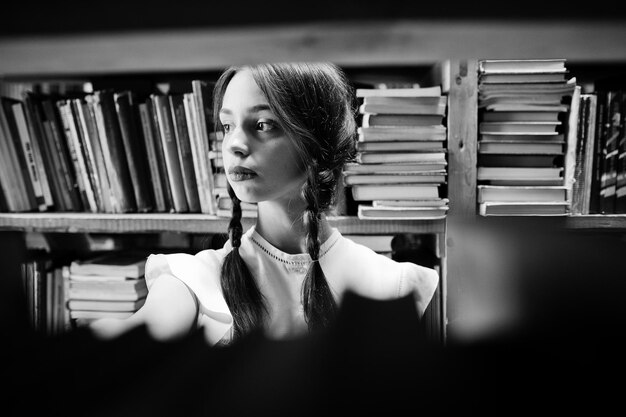 Dziewczyna z warkoczykami w białej bluzce w starej bibliotece