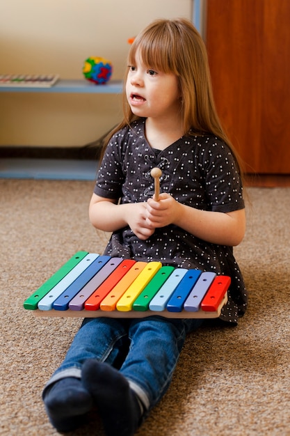Bezpłatne zdjęcie dziewczyna z zespołem downa bawi się kolorowym ksylofonem