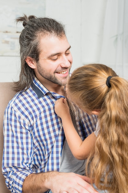 Bezpłatne zdjęcie dziewczyna zapina koszulę jej ojca