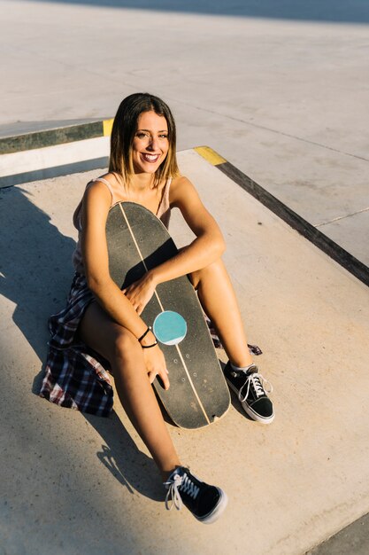 Dziewczynka Skater siedzi i uśmiecha się