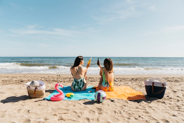 Dziewczyny na plaży opiekania z piwem