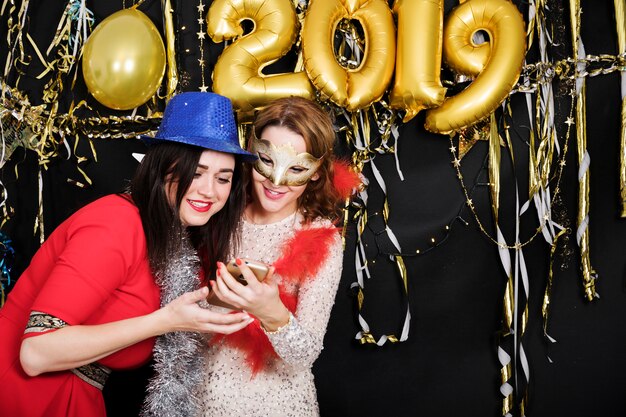 Dziewczyny przy 2019 przyjęciem patrzeje smartphone