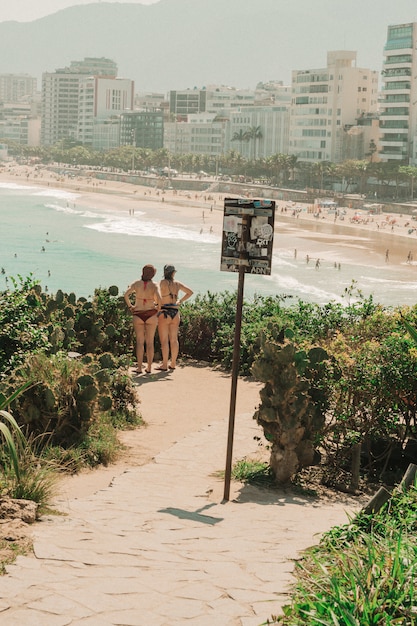 Bezpłatne zdjęcie dziewczyny w bikini stojące i patrzące na plażę w rio de janeiro