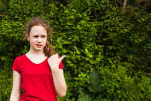 Bezpłatne zdjęcie dziwna dziewczyna wskazuje na bok z kciukiem do góry w parku